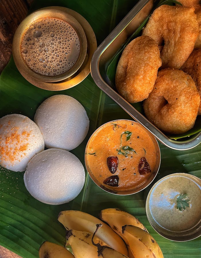 services-03 Delicious South Indian breakfast with idli, vada, chutney, and coffee on banana leaf.